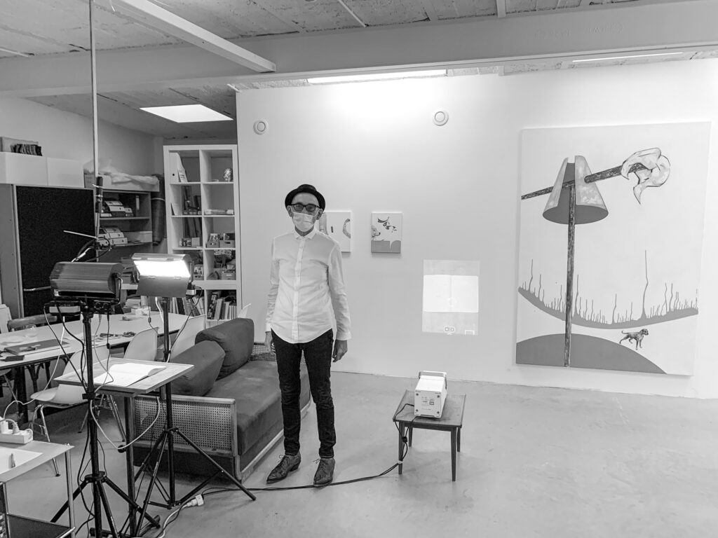 Ausstellungsraum mit dem künstler Matthias Aeberli, Installation mit Tisch, Beleuchtung Skizzenbüchern, projektor und projektion, zwei kleine acryl Leinwände und eine grosse Leinwand