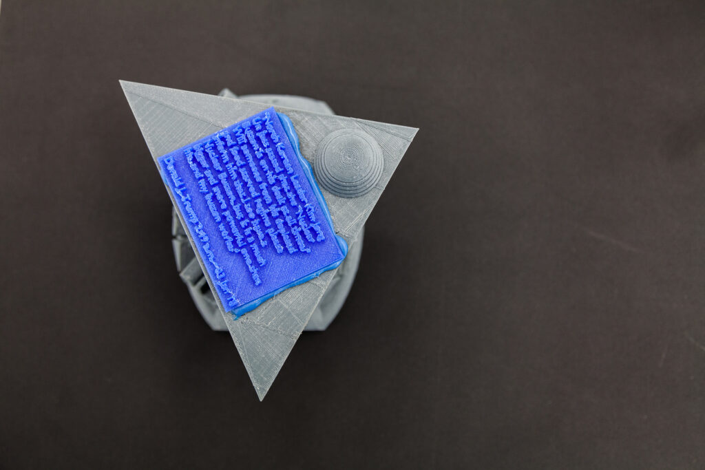 3D printed Objekt, grau mit blauen Textfeld