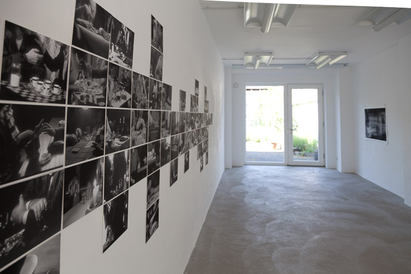 exhibition view with a collage of black-and-white photographies on the wall